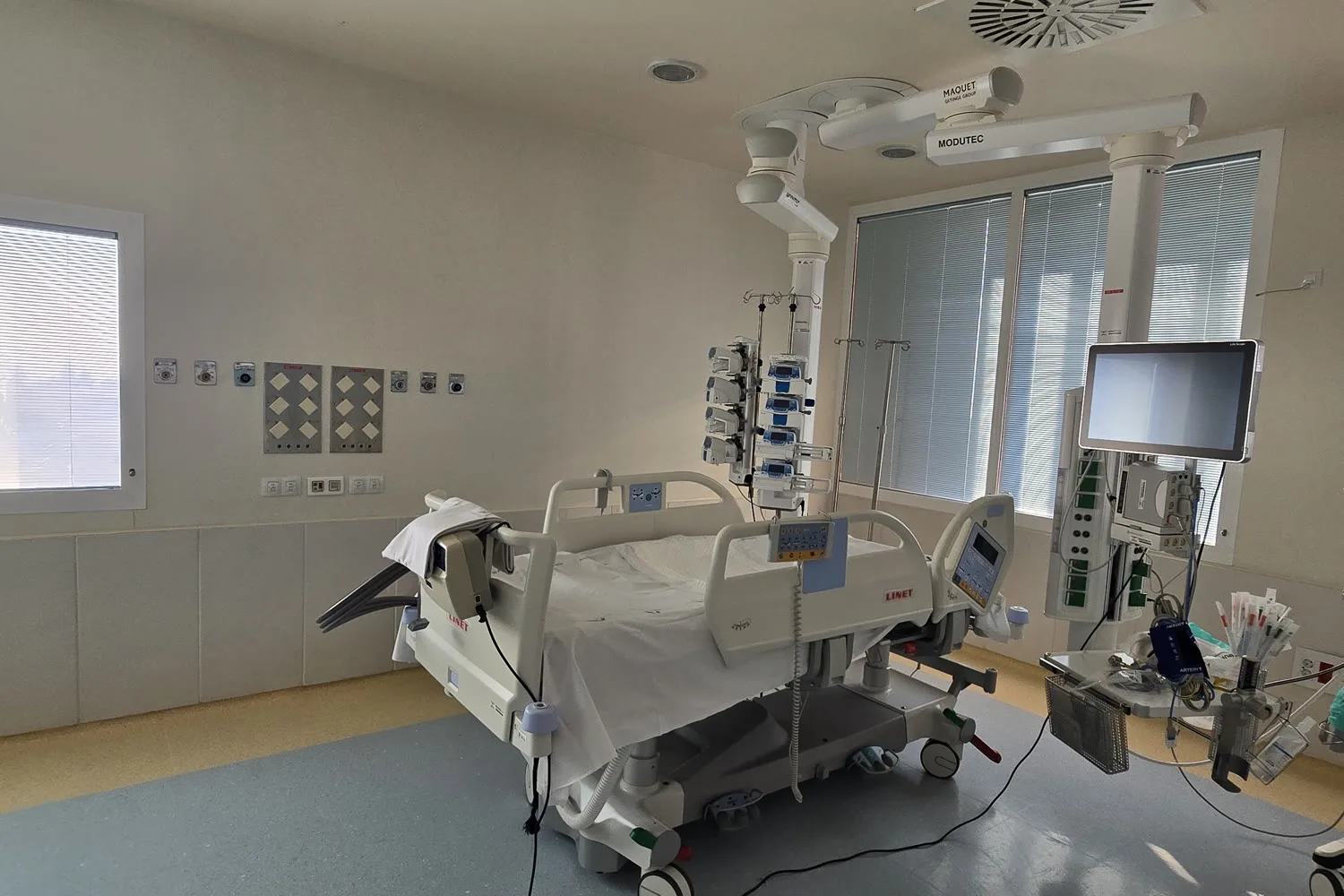 Box de intensivos con la cama, las tomas de gases de la pared de cabecera y la columna de techo