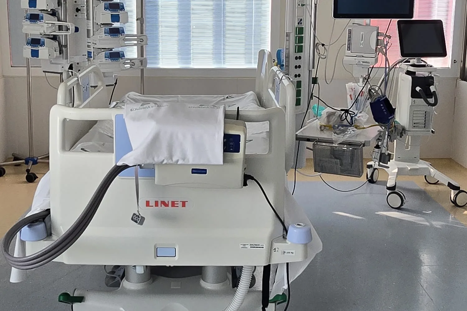 Cama de intensivos con bombas de infusión y respirador junto a la cabecera